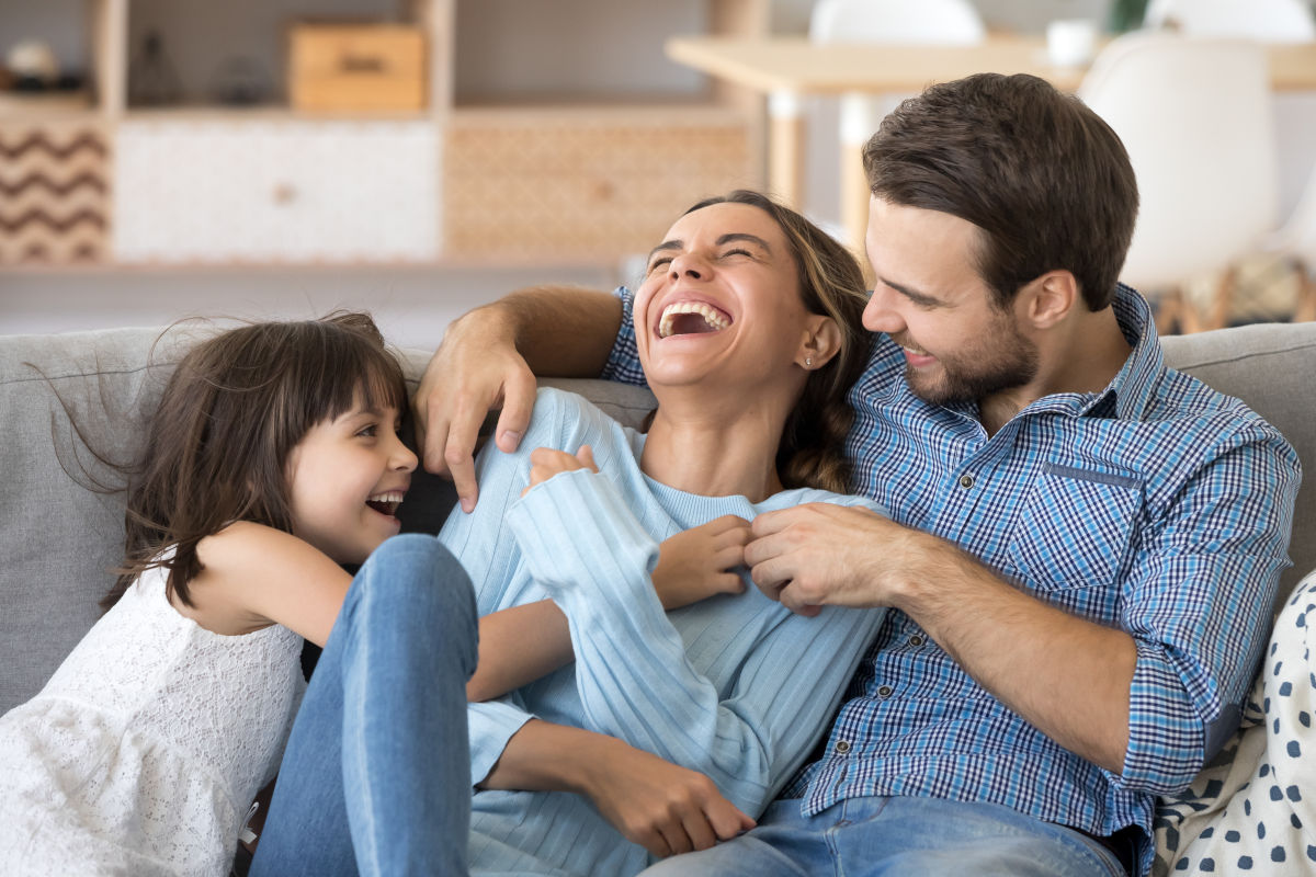 Familie sitzt lachend auf dem Sofa