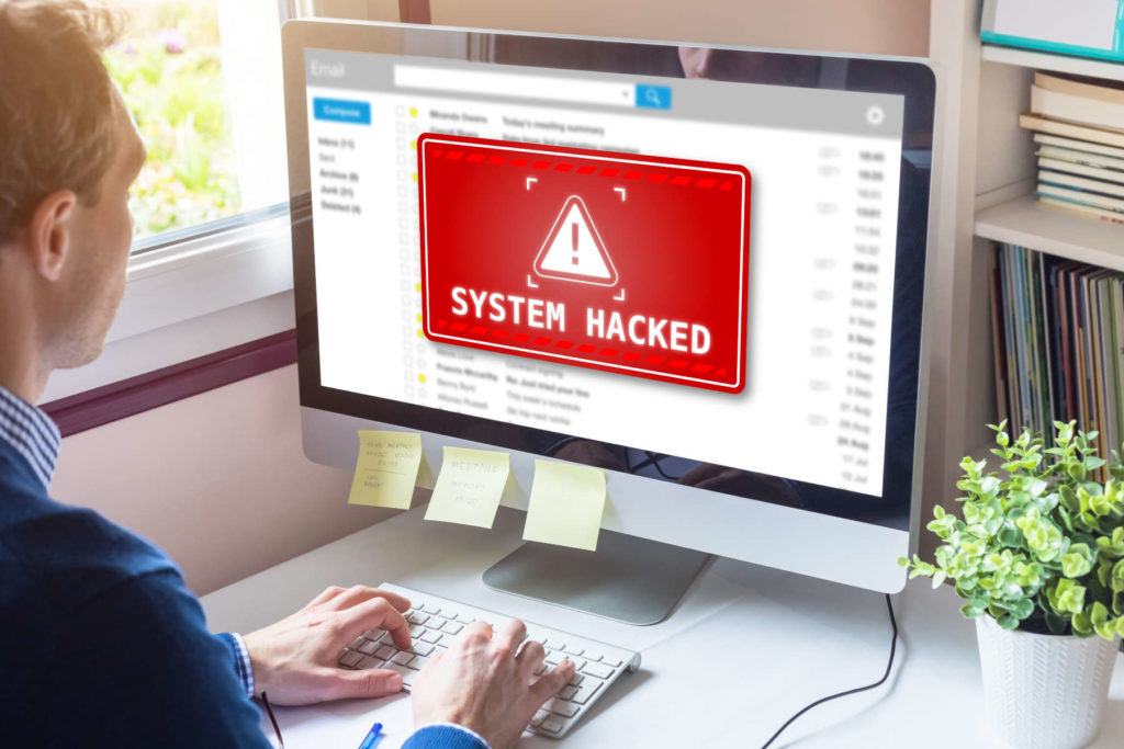 Mann am PC mit Warnung vor einem Hacker-Angriff